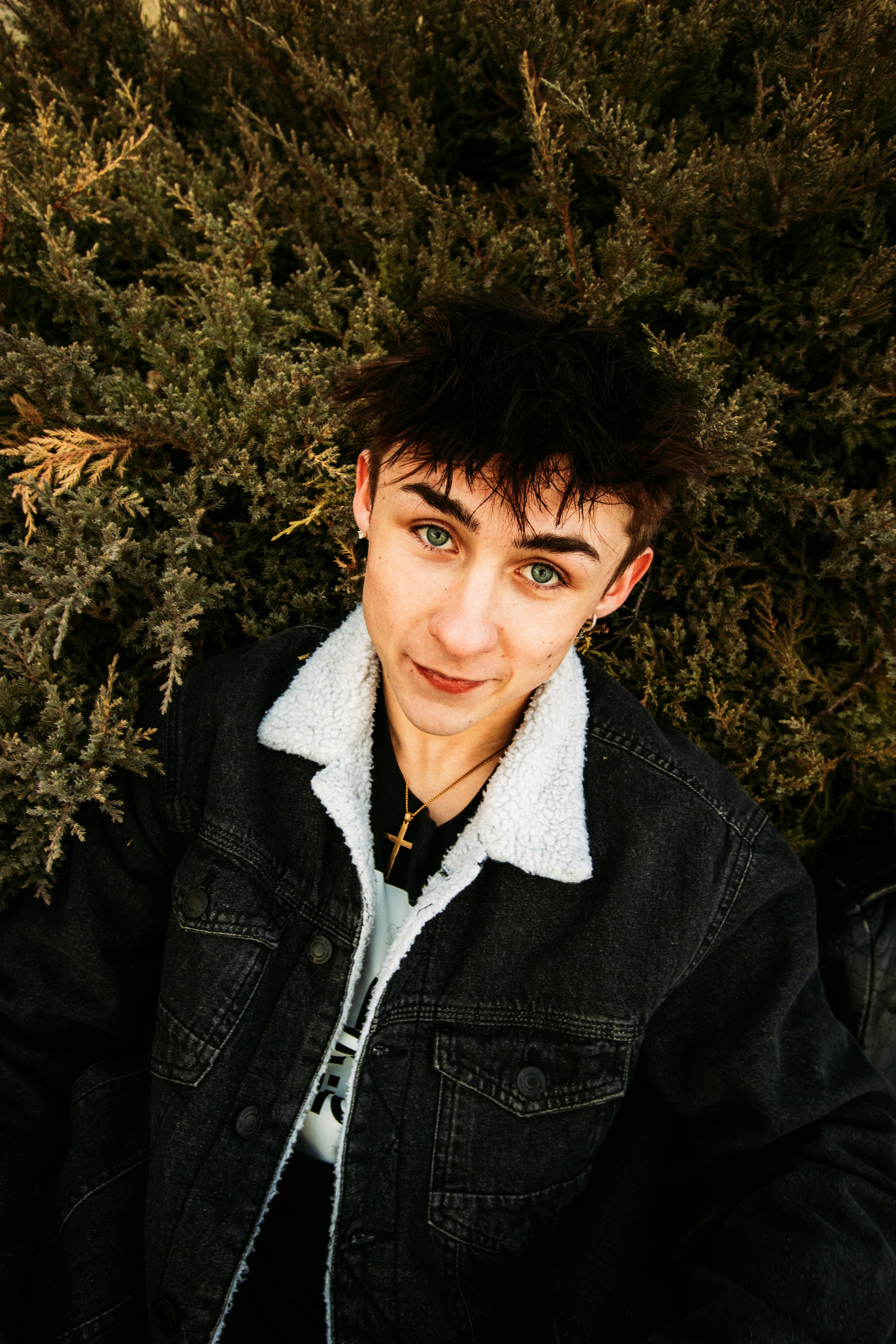 man in black leather jacket lying on brown dried leaves